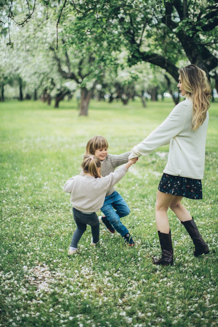 Joyful mother with two kids playing in a blossoming park, capturing a moment of springtime fun and togetherness.